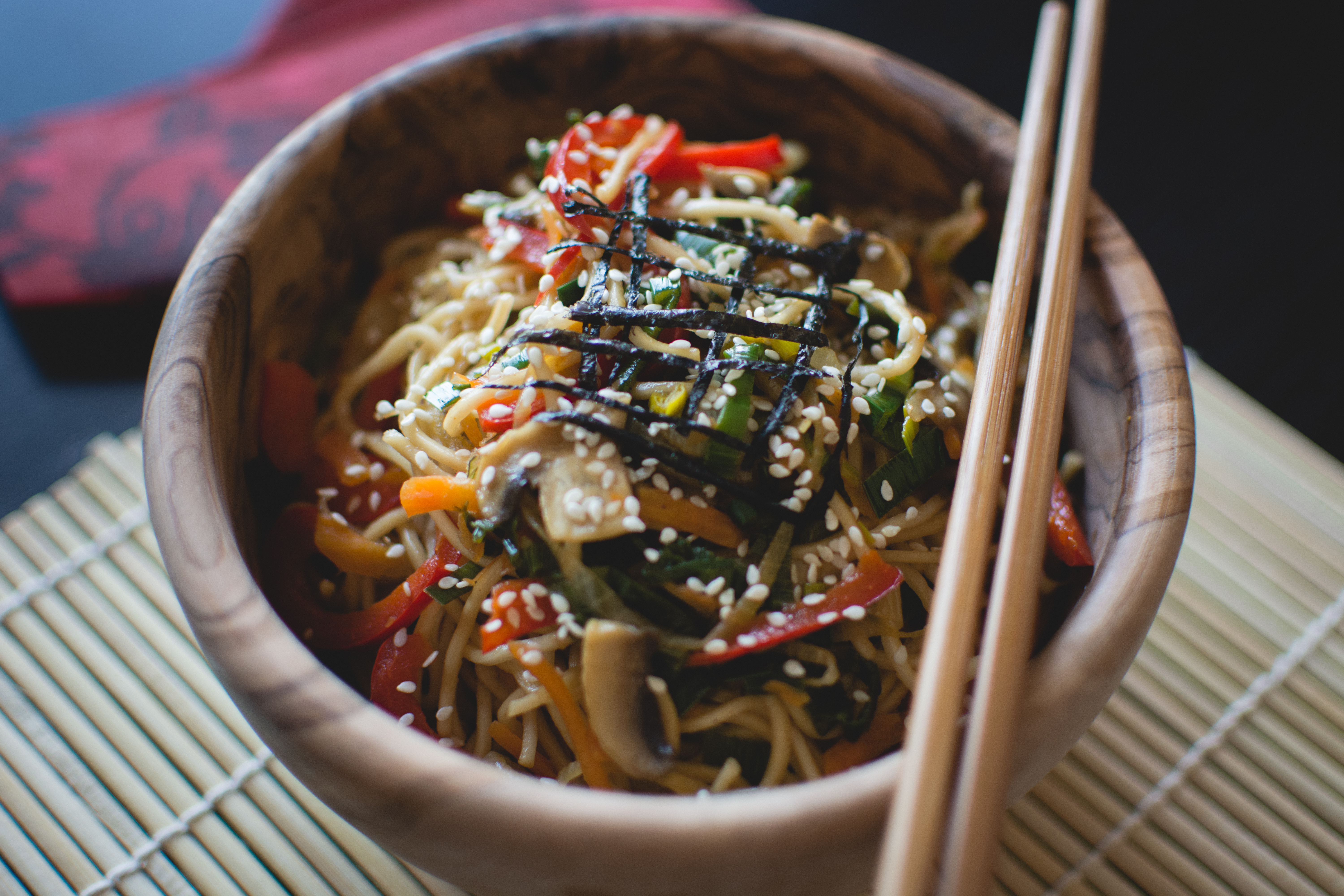 Noodles with vegetables in a wooden bowl with wooden chopsticks